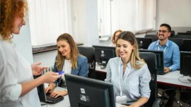 étudiantes et étudiants souriant avec une formatrice devant leurs ordinateurs