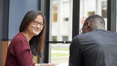 une étudiante souriante et un étudiant de dos