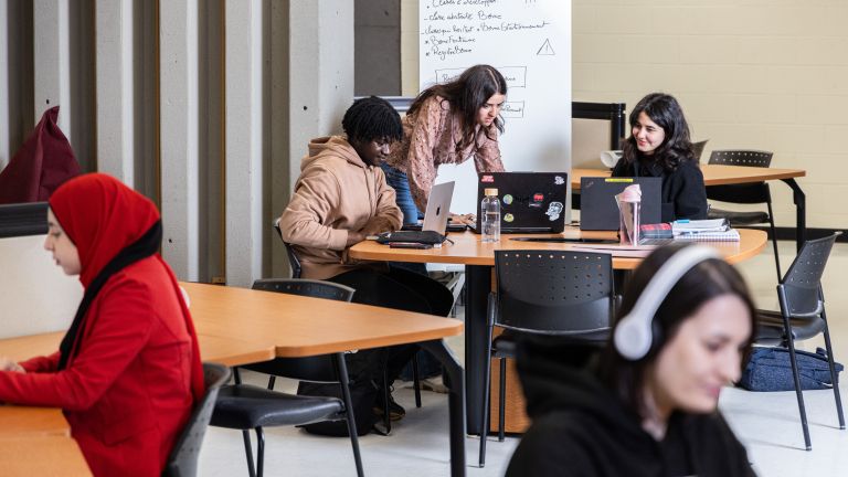 étudiantes et étudiants à une table de travail à la bibliothèque