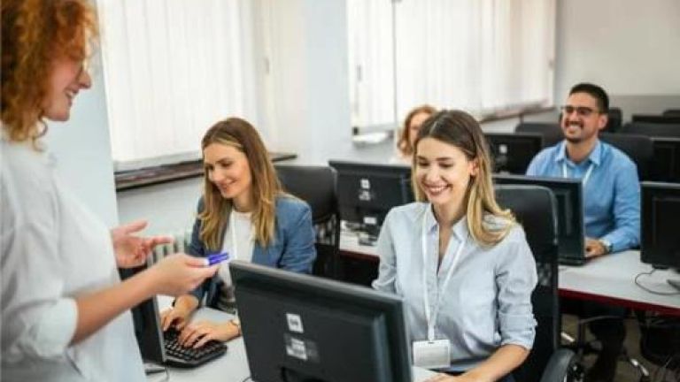 étudiantes et étudiants souriant avec une formatrice devant leurs ordinateurs